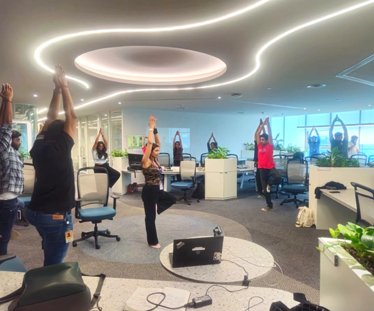 Poonam demonstrating a corporate yoga pose with employees